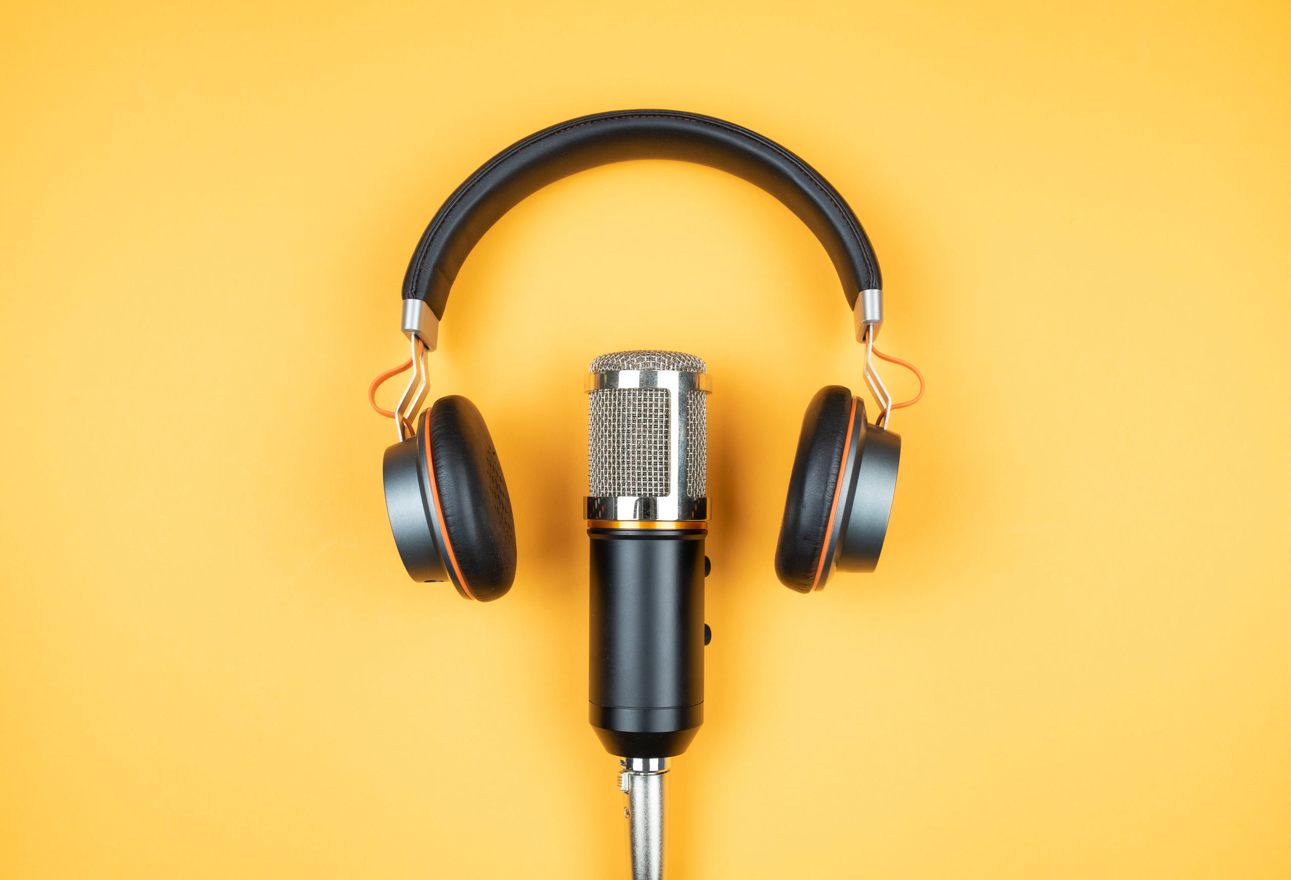 directly above view of headphones and recording microphone on orange background